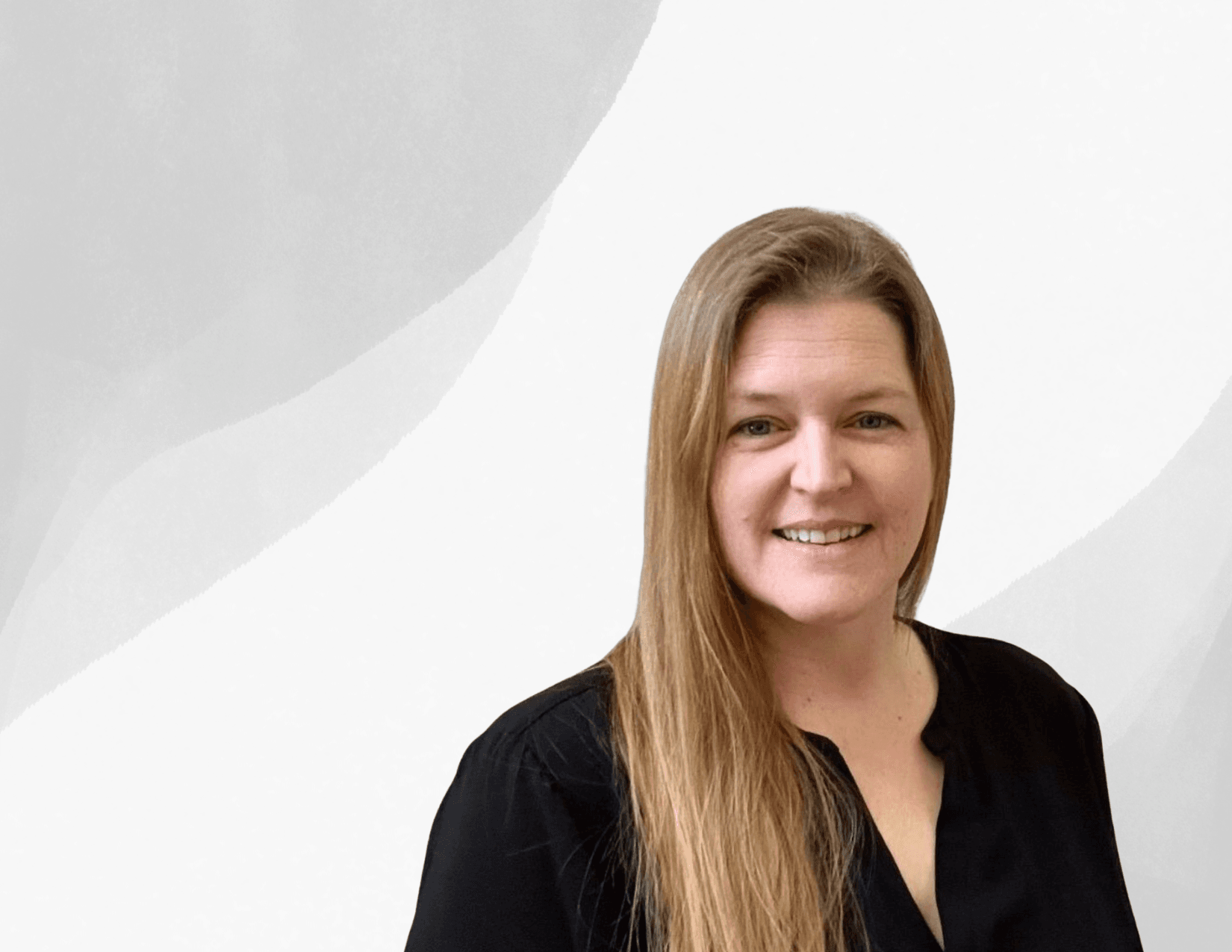 A woman with long blonde hair, wearing a black top, smiles at the camera in front of a light grey and white abstract background.